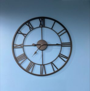 Elegant black wall clock on a blue background.