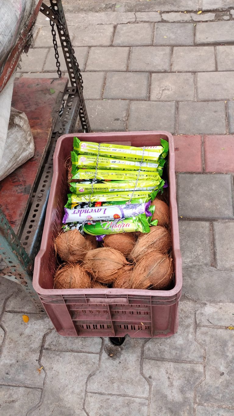 A basket of coconuts and incense placed in front of the temple for devotees.