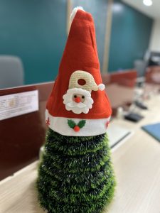 Small artificial desktop christmas tree with a santa hat on top.