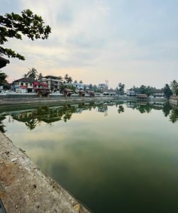 Ancient pond with surrounding stairs, set against a bustling cityscape in the background.