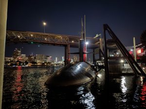 View larger photo: The front of the USS Blueback (SS-581) in the Willamette River in Portland, Oregon at night. The Marquam Bridge is visible in the background.