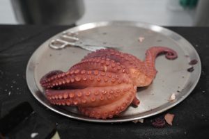 Freshly cooked octopus served on a steel tray, ready for preparing pulpo a feira