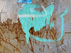 View larger photo: A textured white wall with some blue greenish paint marks and rusty scratches.