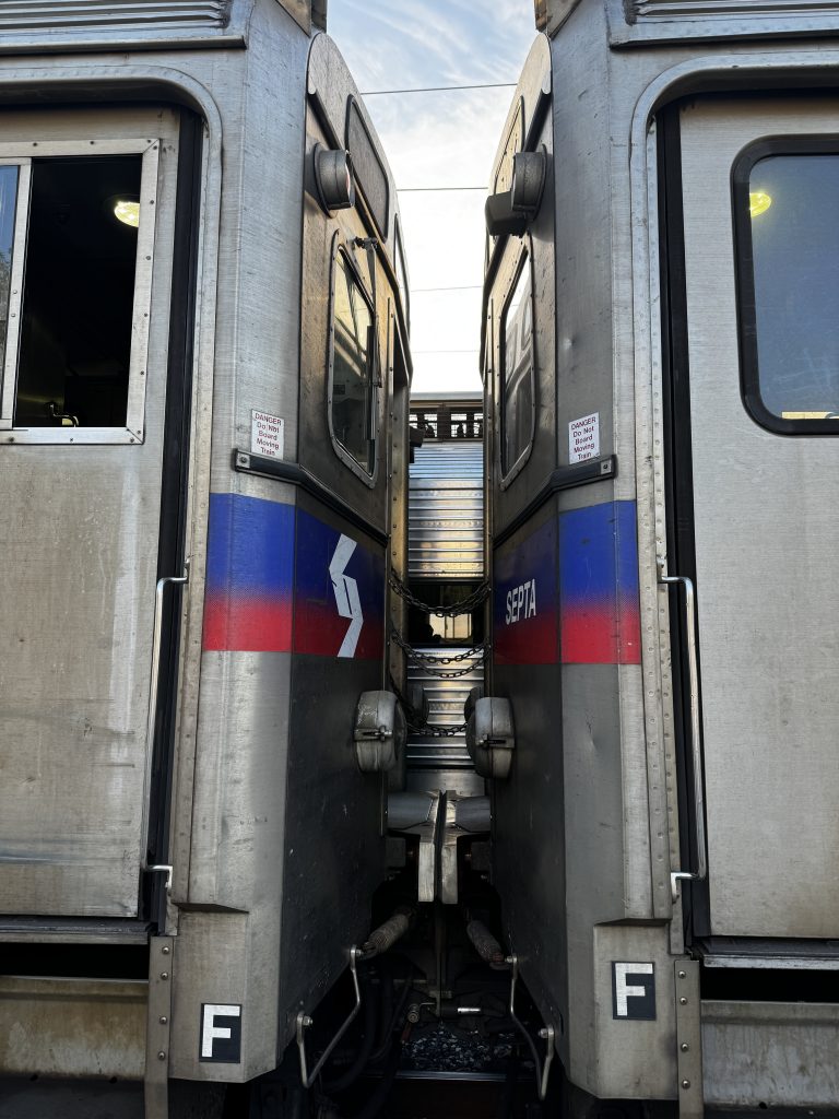 Looking up at two SEPTA regional rail train cars connected. You can see the sky behind it.