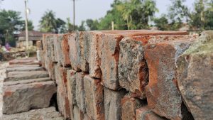 A stack of bricks placed on a rugged dirt road, showcasing their vibrant color against the earthy background.