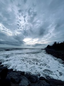 Tranquil beach at dusk, where the blue-grey sky meets calm waters, reflecting the gentle colors of sunset.