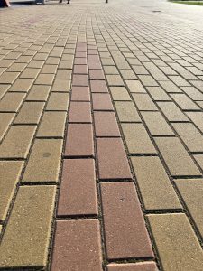 Rectangular yellow tile pavement, with a double line of red tiles tracing a path forward.