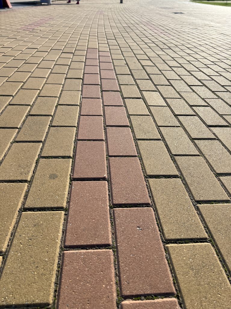 Rectangular yellow tile pavement, with a double line of red tiles tracing a path forward.