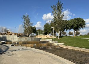 Photo showing a fountain in a park with trees and clouds in the background