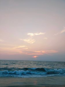 A serene sunset over the ocean with gentle waves crashing onto the shore