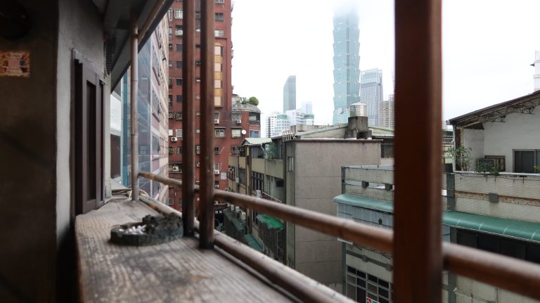 view from a balcony with the image of Taipei 101 in the far distance covered by morning clouds.