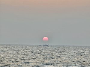 Long view of sunset and fishing boats. From Kozhikode beach, Kerala, India.