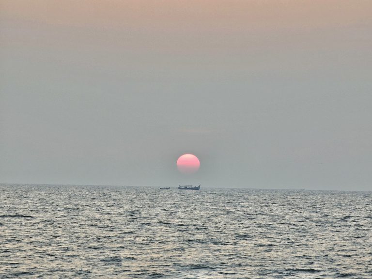 Long view of sunset and fishing boats. From Kozhikode beach, Kerala, India.