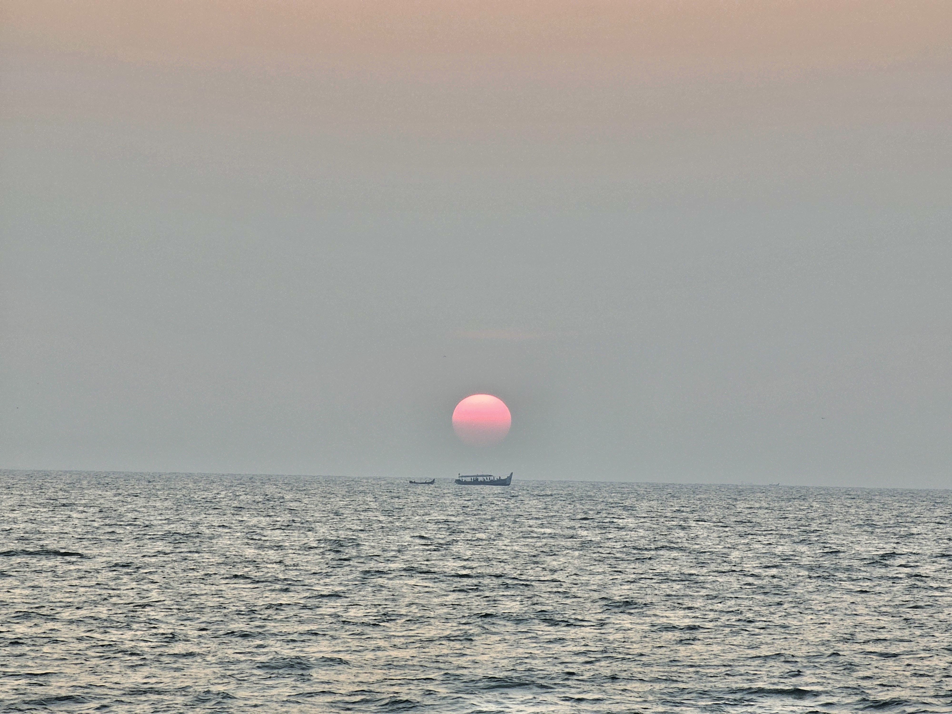 Long view of sunset and fishing boats. From Kozhikode beach, Kerala, India.