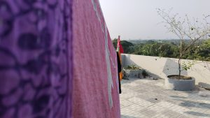 A serene balcony view showcasing a tree and a towel, inviting relaxation with a comforter in the background.