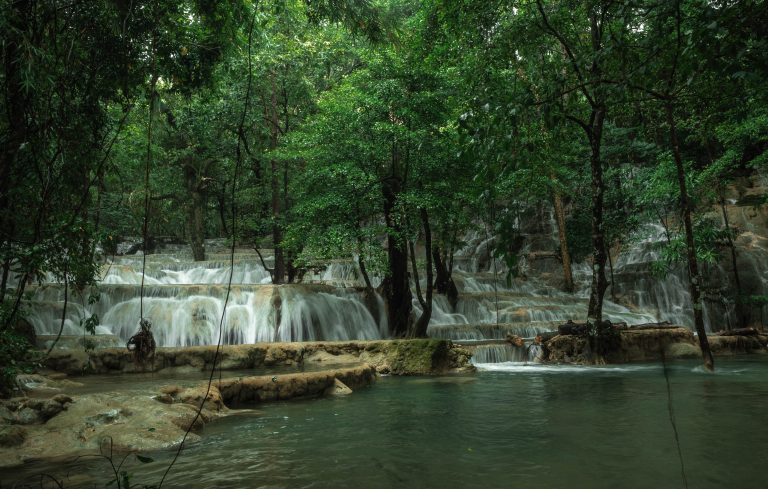 Majestic tiered limestone terraces of Kaparkan Falls in Tineg, Abra, cascading with crystal-clear waters surrounded by lush green forest, creating a breathtaking natural wonder in the heart of the Philippines.