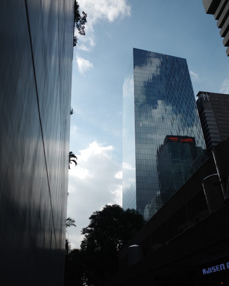 A tall glass front building stands against a cloudy, gloomy sky.