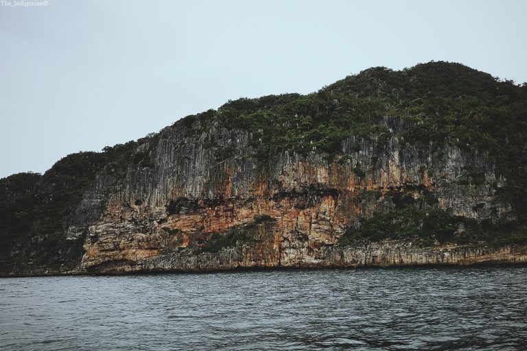 A solitary rock formation stands tall in the ocean waters off the coast of Guimaras, Philippines.