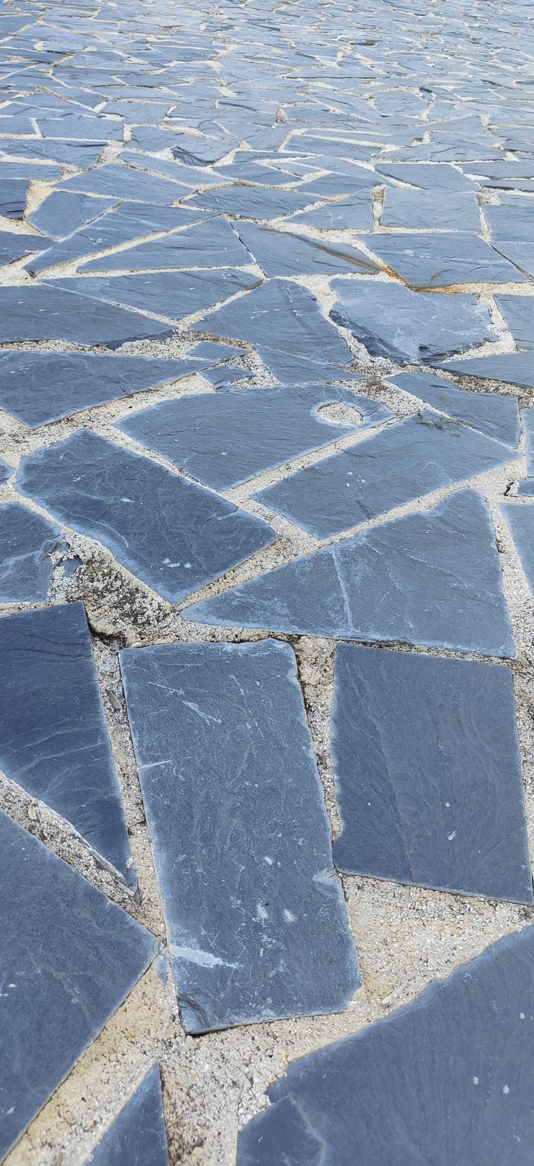 Path made of slate stone tiles. All of them with different and irregular shapes.