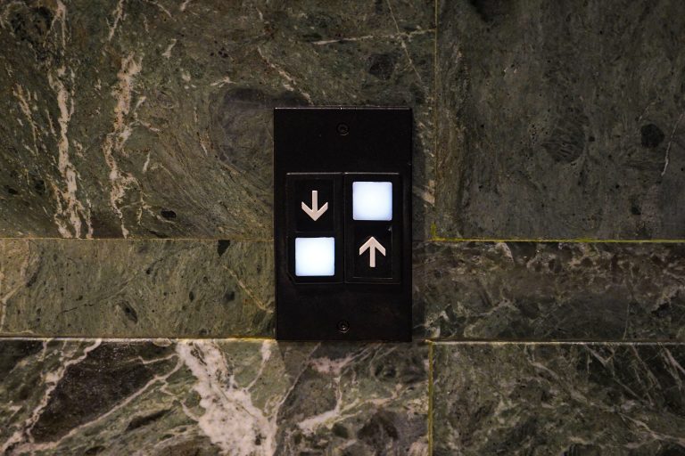 Confusing elevator controls placed on a green marble surface