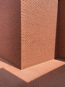 VitraHaus. A sunlit corner of a building with red brick walls and a red brick floor, casting distinct shadows on the ground.