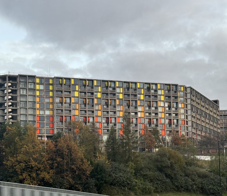 A building adorned with many windows, perched elegantly on the side of a hill, showcasing a picturesque view.