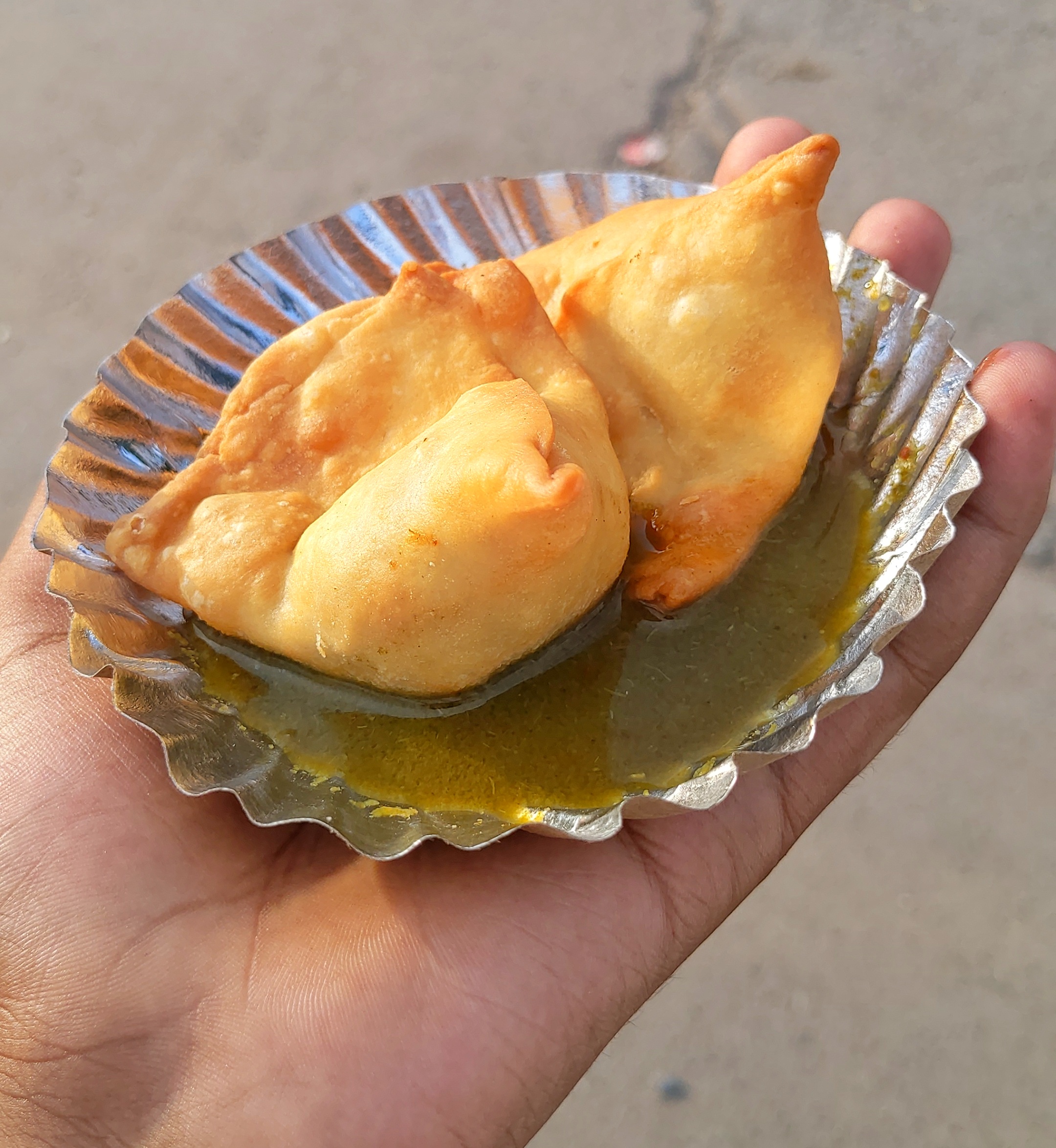 Two mini samosa in plate with green sauce