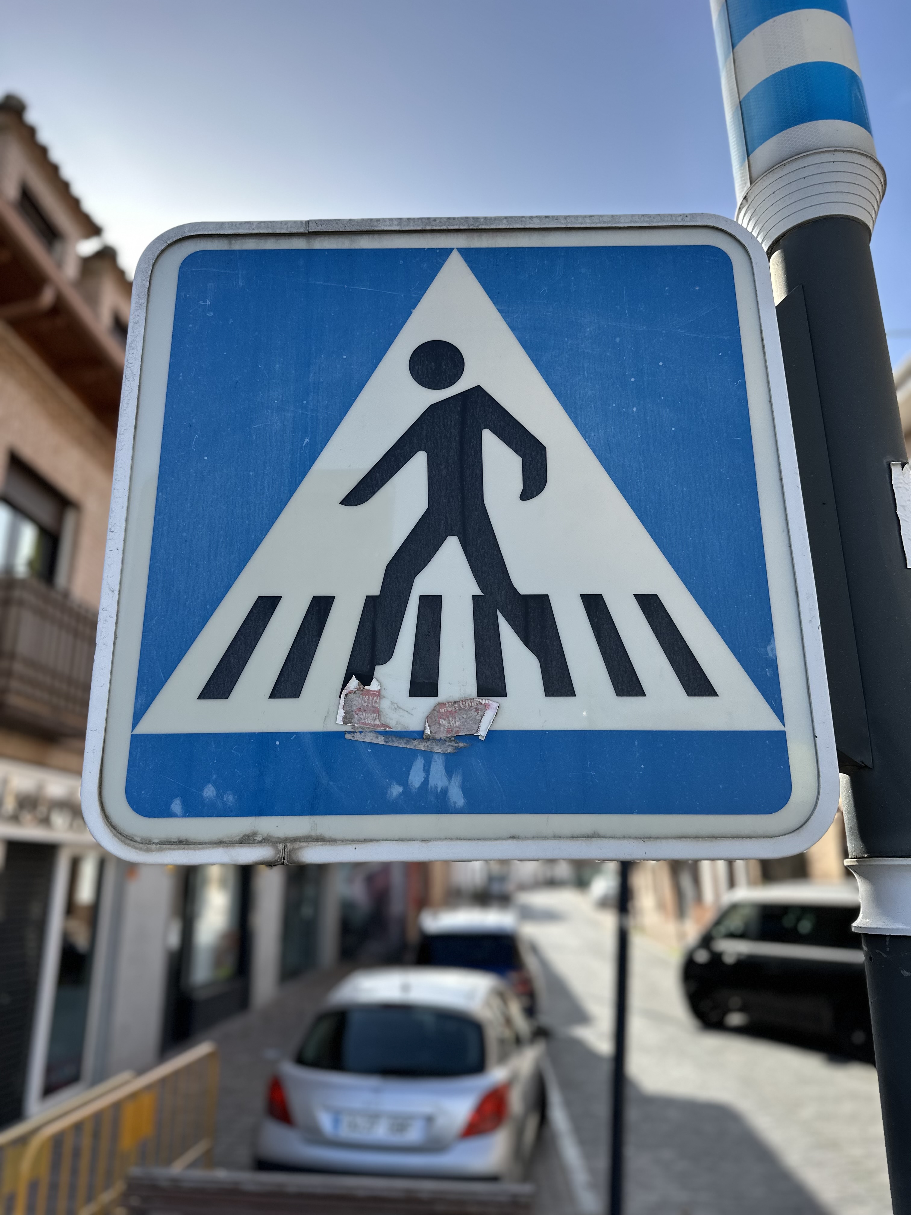 A blue and white pedestrian crossing sign with a silhouette of a person walking.