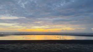 The sun sets beautifully over the ocean at inani beach, cox bazar, reflecting warm hues on a peaceful body of water.