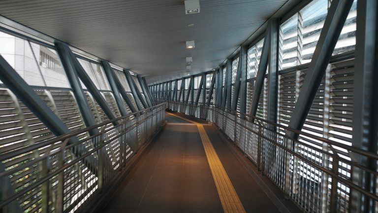 A walkway featuring a railing alongside a prominent yellow line, guiding pedestrians safely along the path.