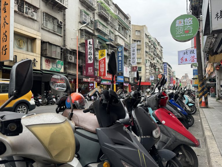 A row of mopeds parked along a street curb in taipei, taiwan.