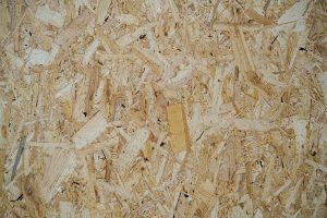 Close-up view of an oriented strand board (OSB) surface, showing the textured and irregular arrangement of wood chips bonded together.