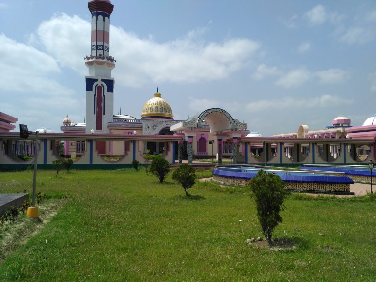 A vibrant mosque with a tall minaret and a central dome featuring intricate designs.