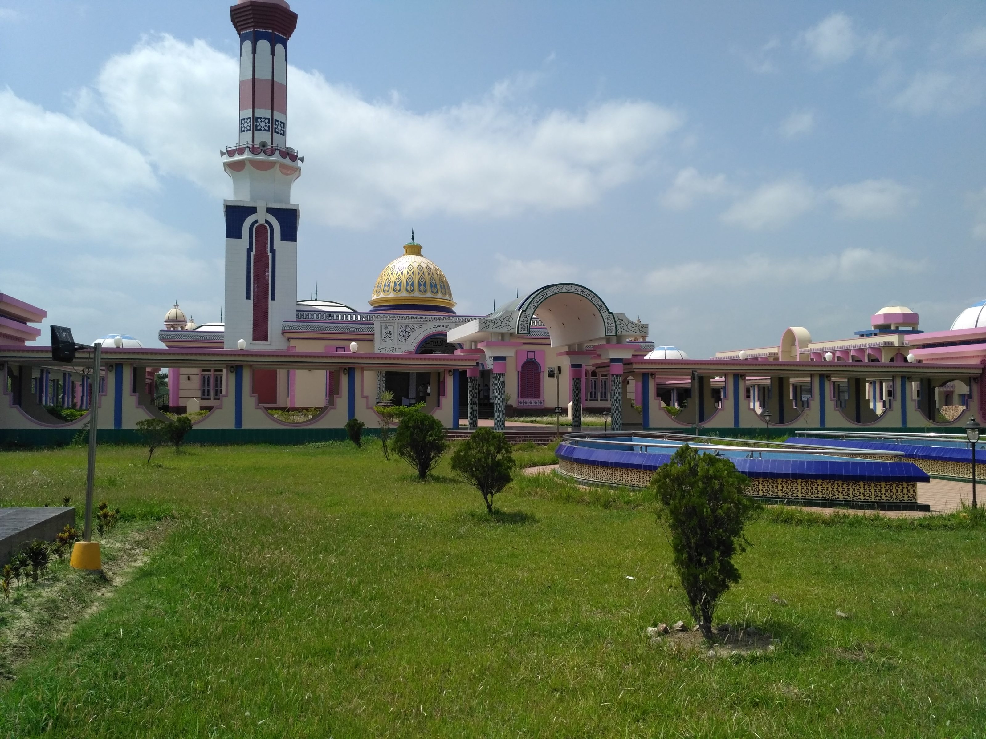 A vibrant mosque with a tall minaret and a central dome featuring intricate designs. 