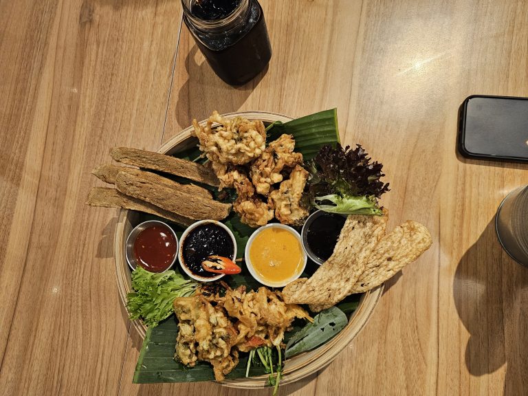 A basket full of starter items in a restaurant in Malaysia. It has a different variety of sauces.