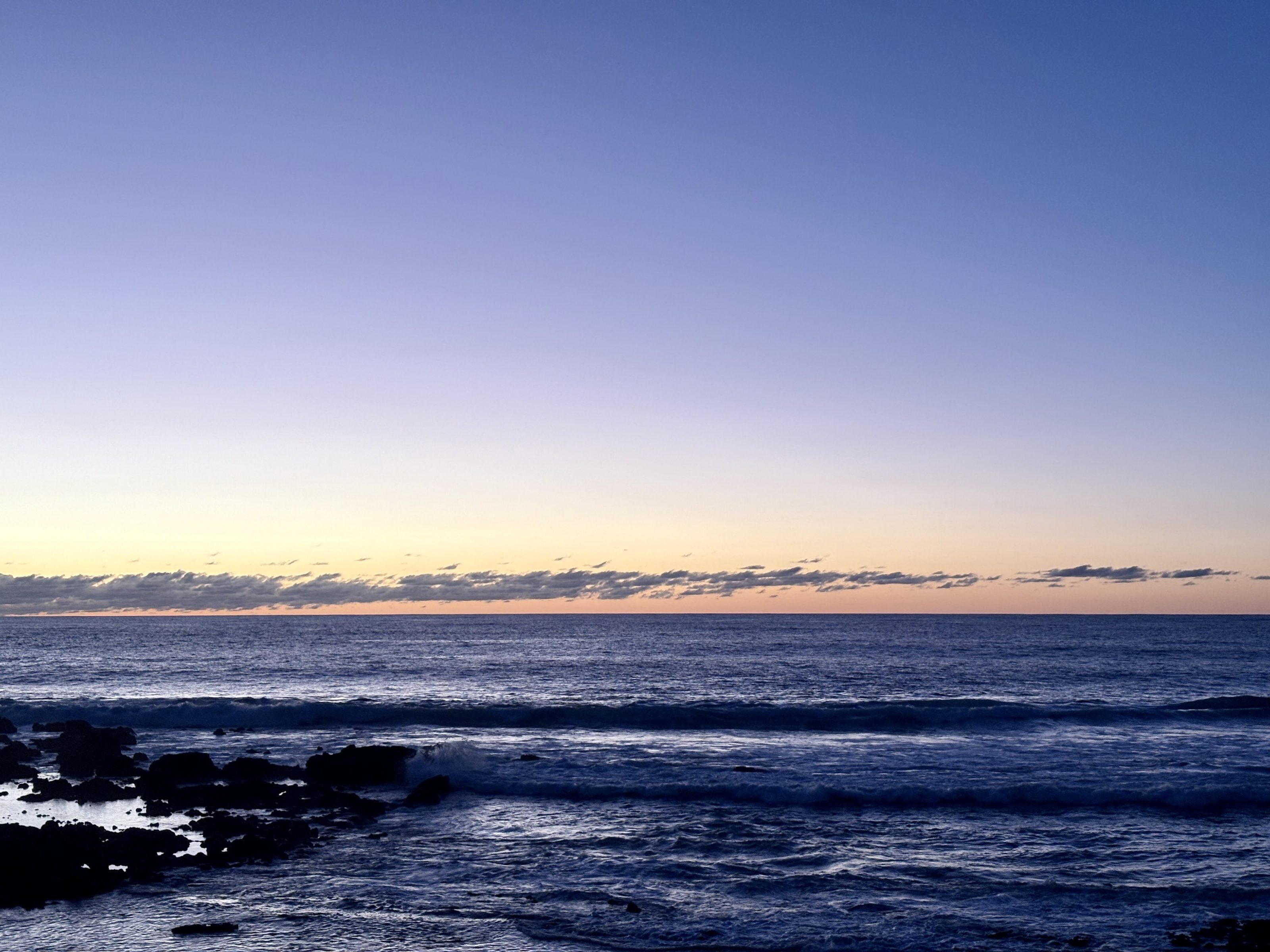 Sunset over water on a beach.