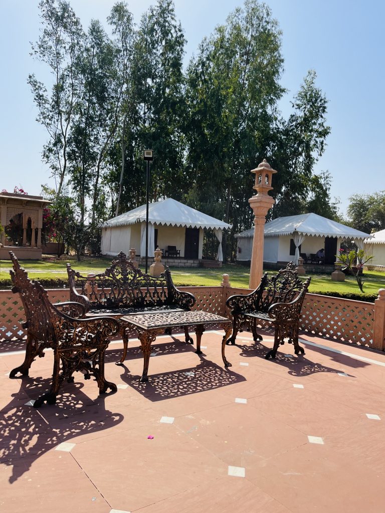 This image depicts an outdoor seating area featuring intricately designed wrought iron furniture, including benches and a table, arranged on a tiled platform.