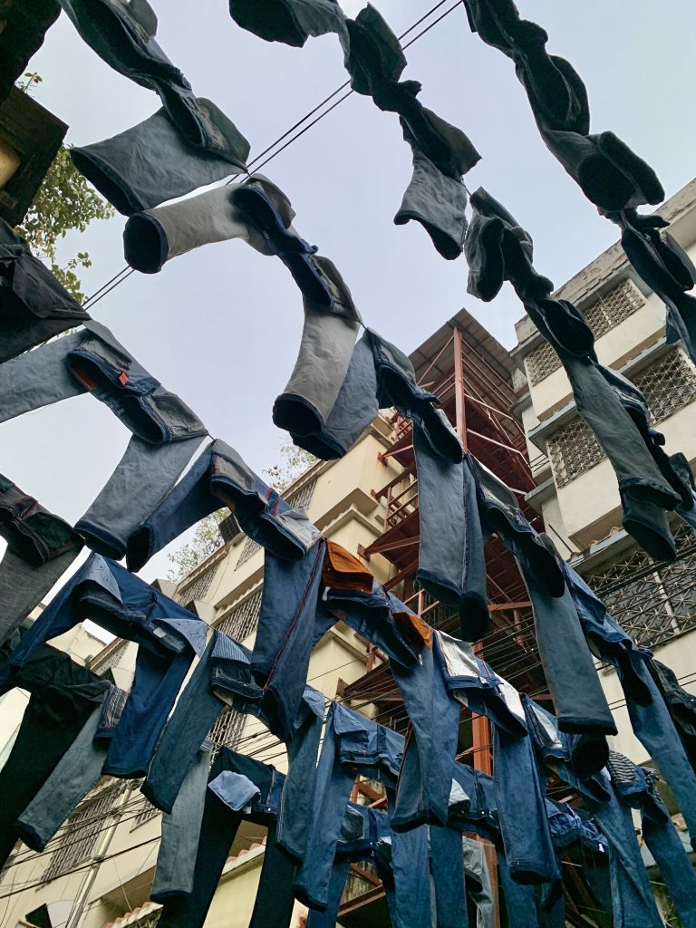 Jeans pants hanging on clotheslines outdoors, seen from below with buildings.