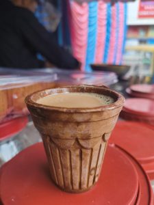 A close-up of a traditional clay cup filled with tea, placed on a red surface. 