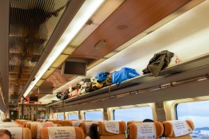 Interior of a train with luggage stored on overhead shelves