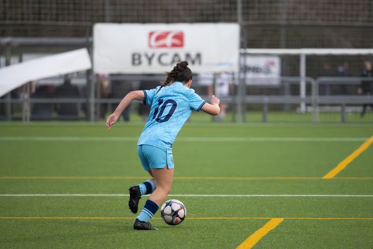 Female soccer player running with ball and number 10