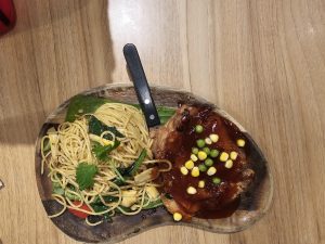 A chicken piece with hot sauce and fry noodles in it. A knife is also there to cut the chicken into pieces. It is one of the popular foods in Malaysia. 