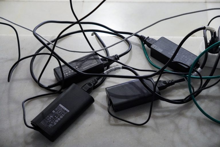 Several black power adapters and tangled cables on a light surface.