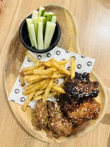 A plate full of Chicken roast, french fries, pieces of cucumber and served on the table. 