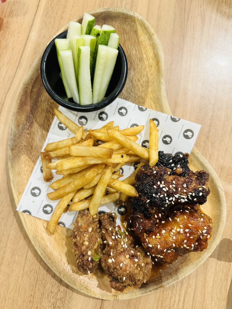 A plate full of Chicken roast, french fries, pieces of cucumber and served on the table.