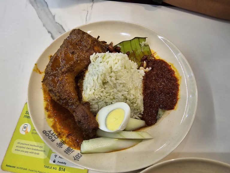 A plate full of rice, chicken leg piece, half-boiled egg, salad and pickle. This type of food is popular in Malaysia.