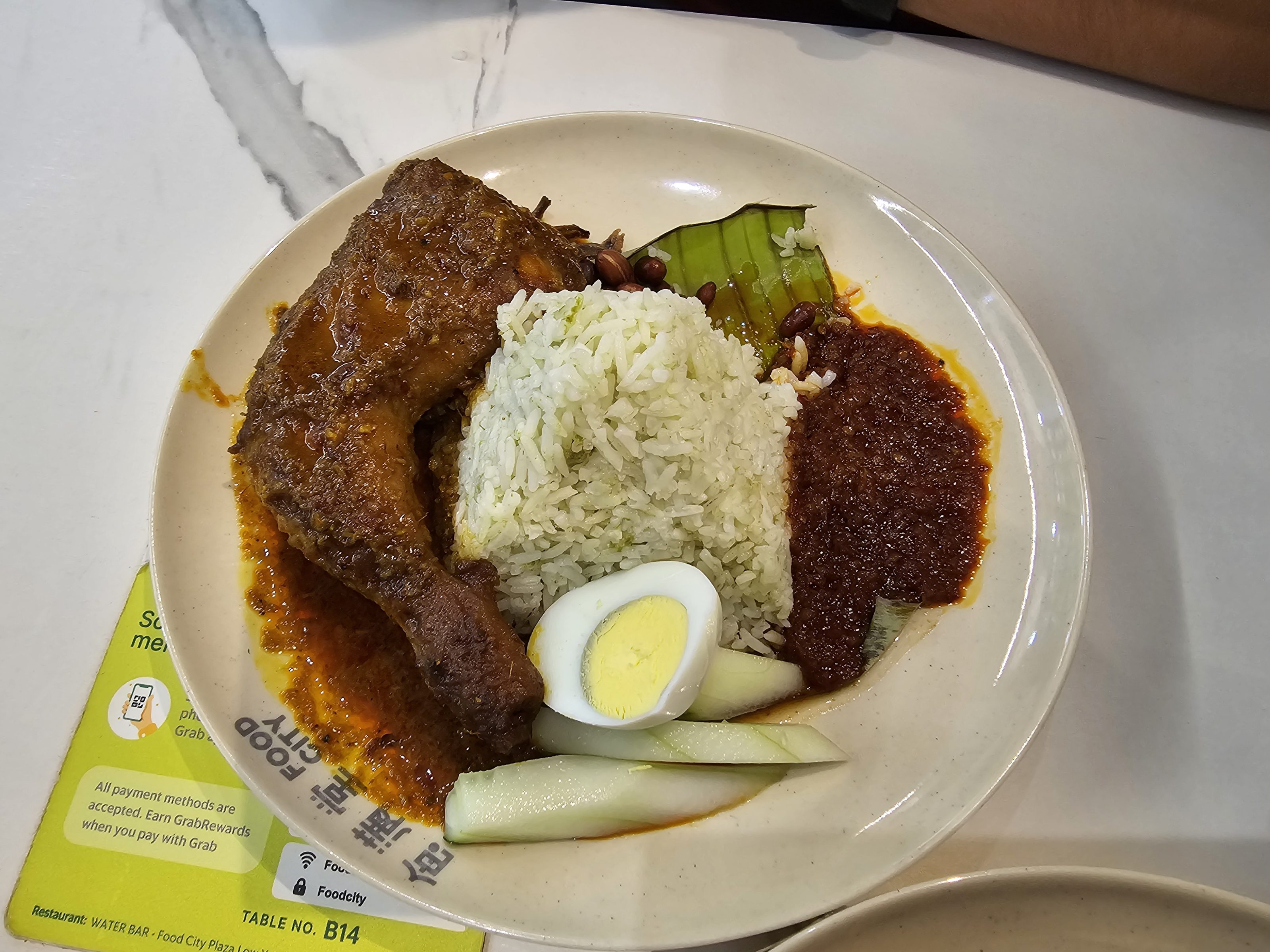 A plate full of rice, chicken leg piece, half-boiled egg, salad and pickle. This type of food is popular in Malaysia.  