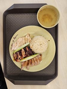 A circular plate with rice, chicken pieces, salad and a bowl of soup on the tray. Which is ready to serve to the customer in a restaurant of Malaysia. 