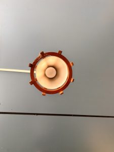 A ceiling view of a circular ceiling light fixture with a metal rim and glass cover, against a gray background. 