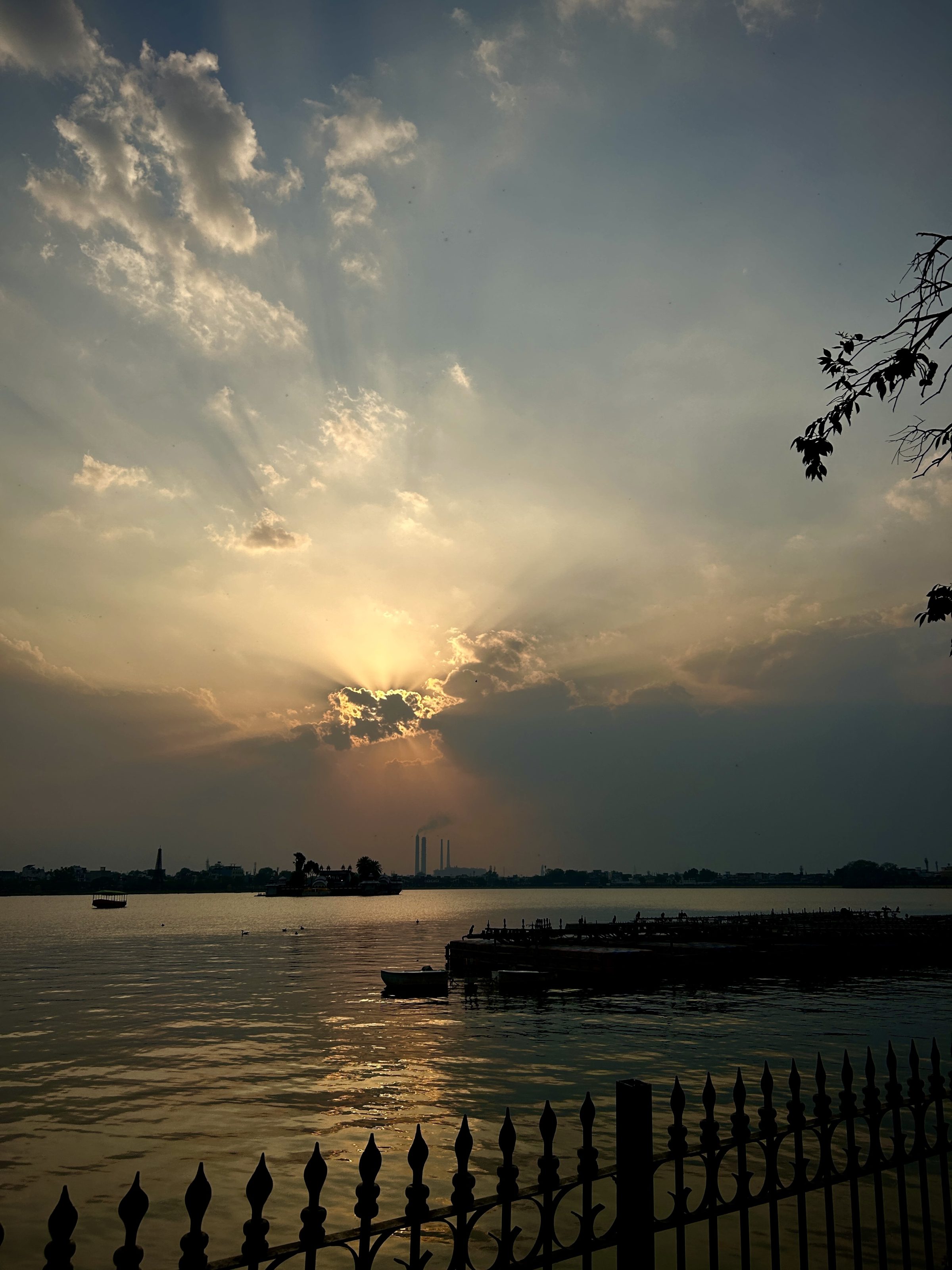 A tranquil lake reflecting the vibrant hues of a setting sun. The water is calm, mirroring the soft oranges, pinks, and purples of the sky. Silhouettes of trees and distant hills frame the peaceful landscape, while the fading light casts a golden glow on the surface of the water, creating a serene and breathtaking atmosphere.